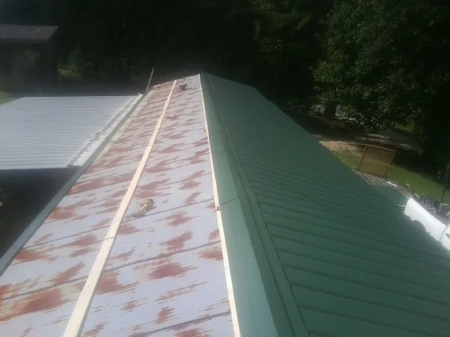 Old rusted panels beside newly installed green metal roofing — Wind Damage Roof Repair by Roofing Brothers in West Hollywood