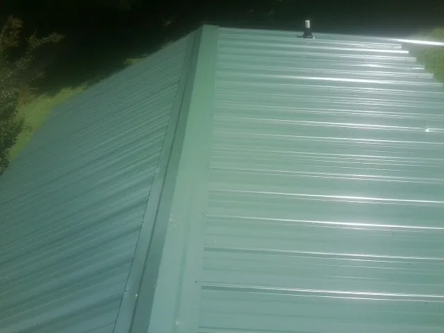 New green metal panels meeting at the ridge of a roof — Flat Roof Repair work by our crew in West Hollywood