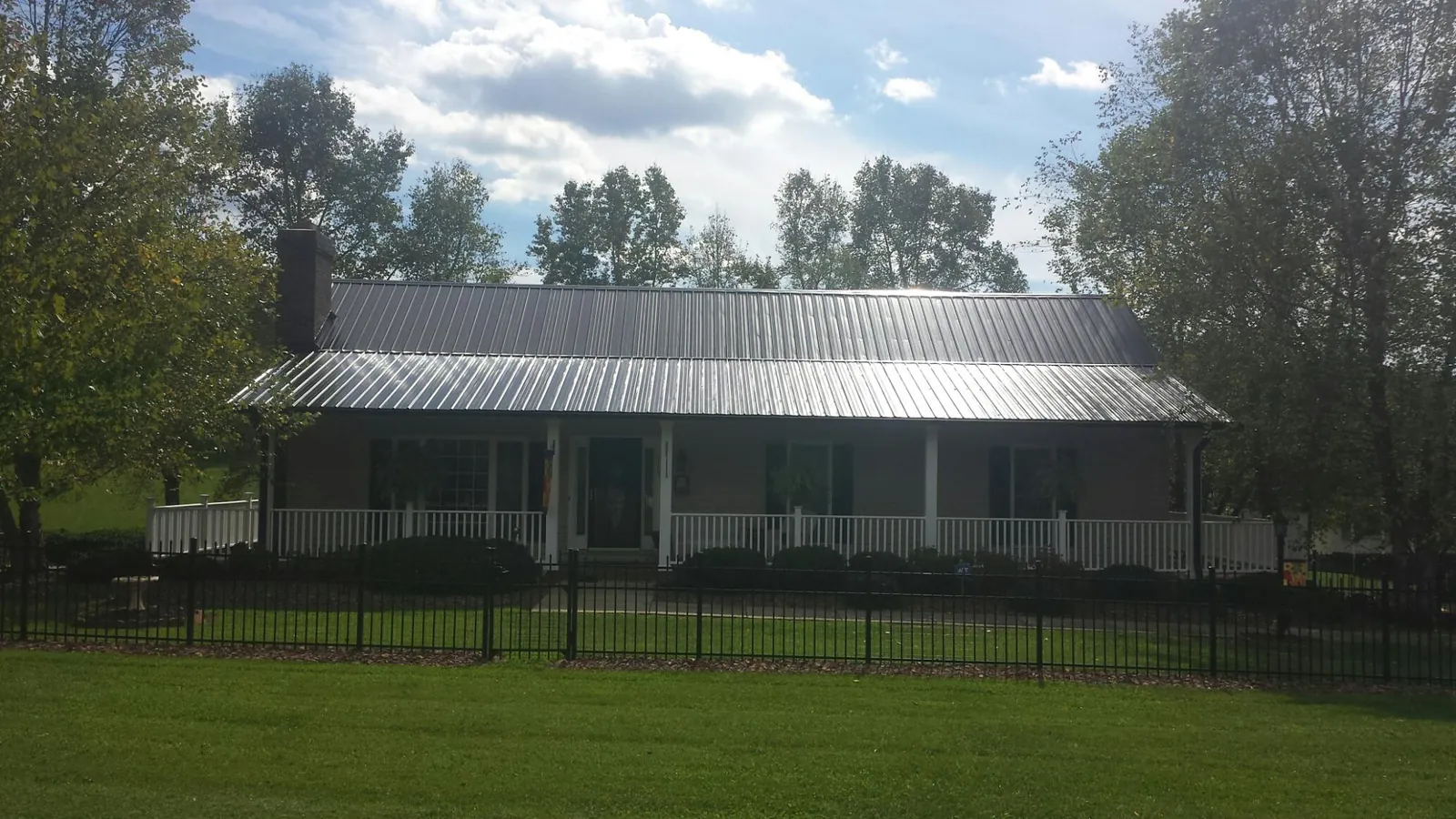 Gray metal roof on a brick ranch with a full width front porch — Gutter Guard Installation work by our crew in West Hollywood