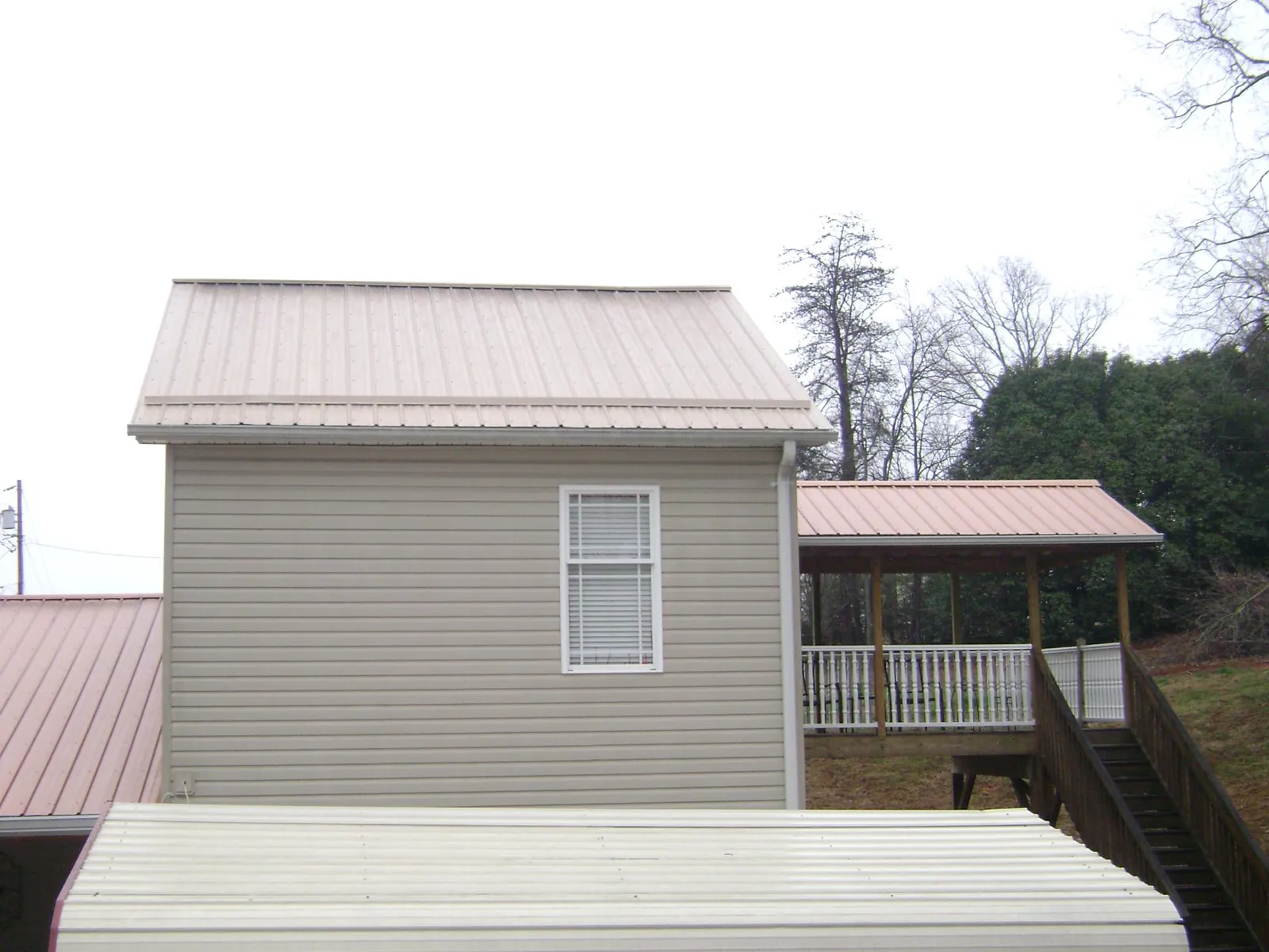 Tan metal roofs on a two story addition and attached porch, from a Roof Replacement job in West Hollywood