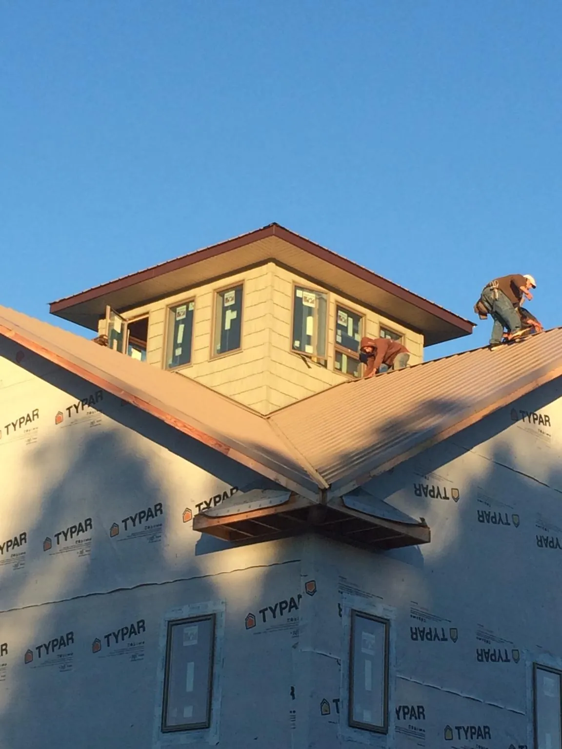 Roofers working around a rooftop cupola on a new metal roof at sunset — Roof Waterproofing in West Hollywood by Roofing Brothers